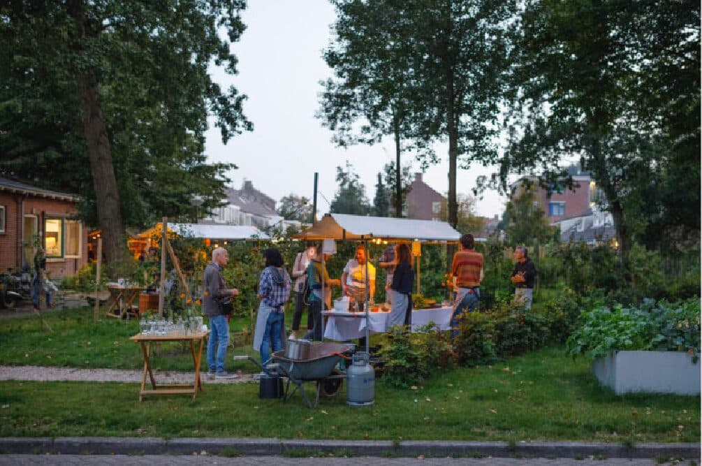 Een buurtfeest in een tuin met kraampjes en lichtjes